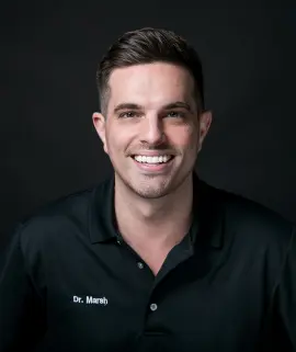 Smiling man with short hair, arms crossed, wearing a black polo with "Dr. Hirsch" embroidered on it. Dark background; professional and approachable.